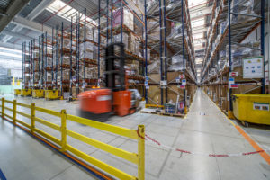 Industrial warehouse for logistics with a folklift in action among the huge shelves