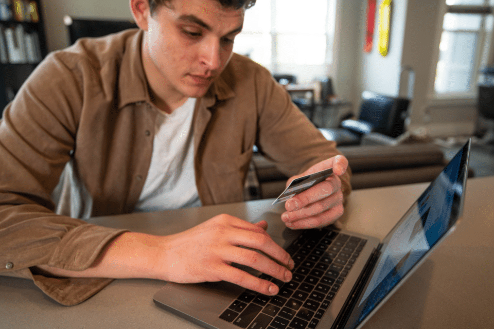 Man looking at his card in front of a laptop.