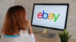 Image of a woman sitting down and looking at her computer screen that has the eBay logo displayed.